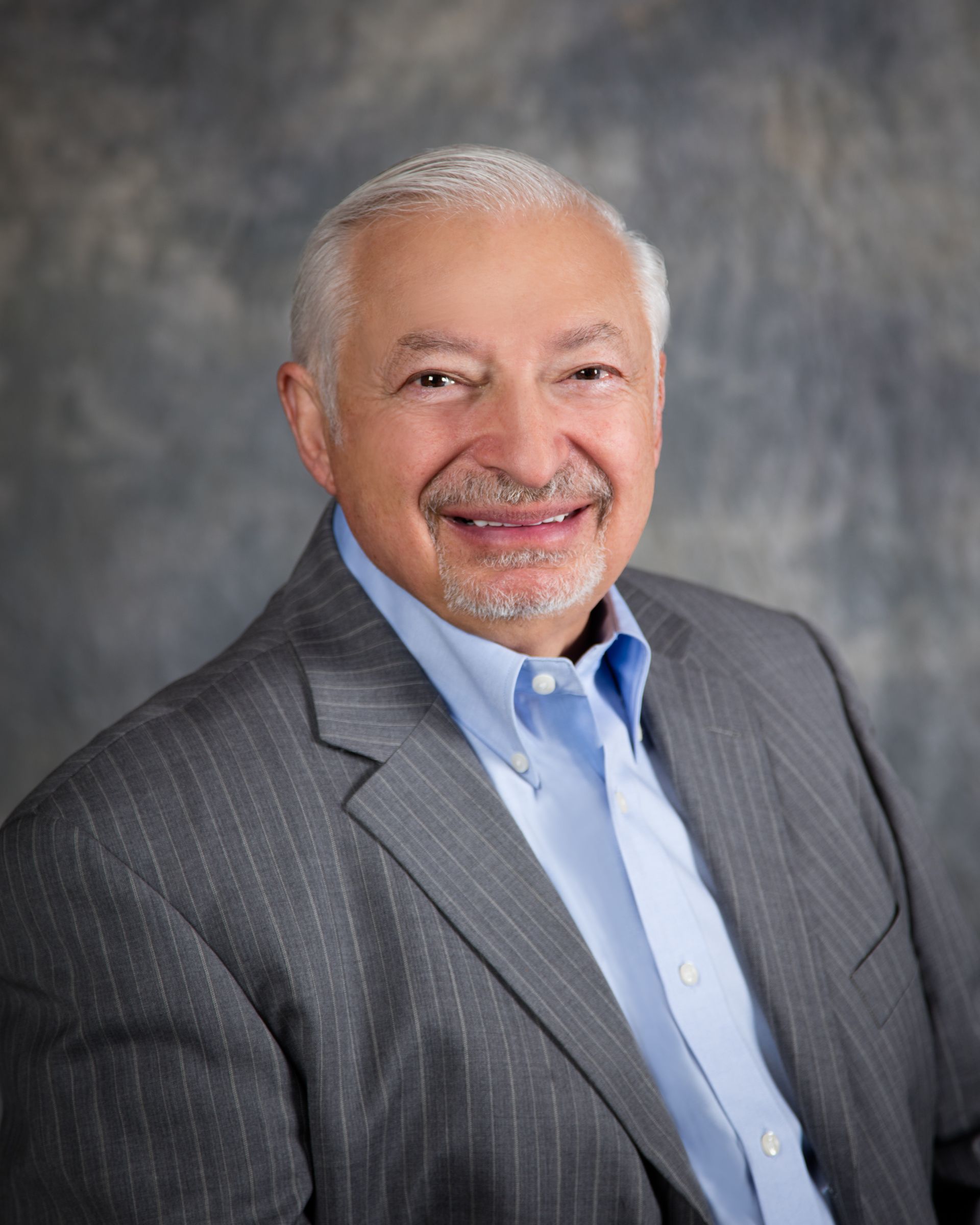 A man in a suit and blue shirt is smiling for the camera.