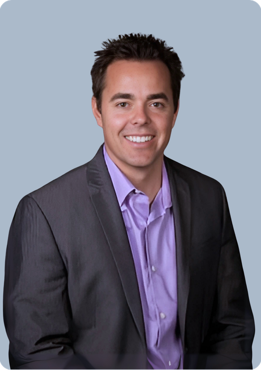 A man in a suit and tie is smiling with his arms crossed.