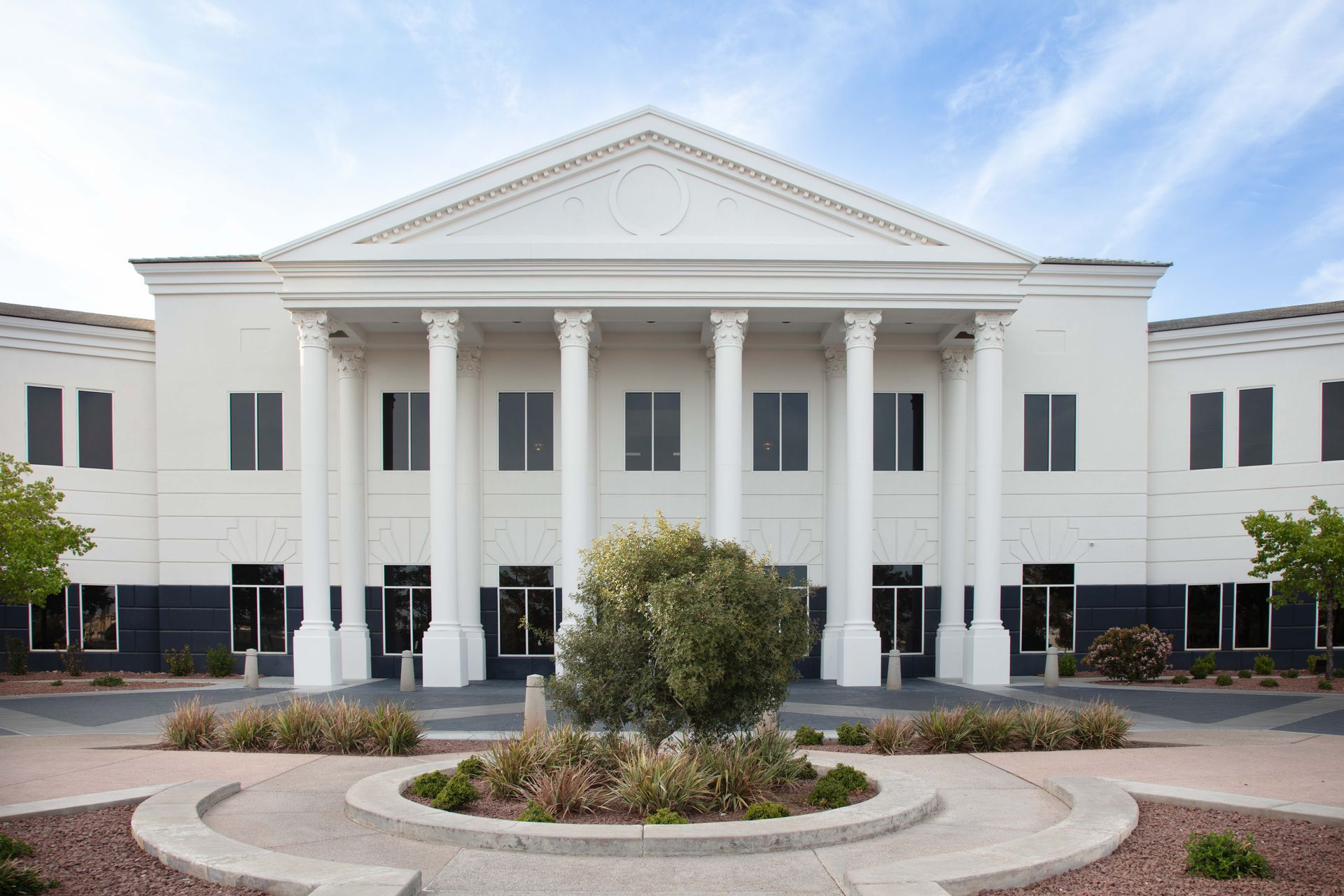 A large white building with columns and a tree in front of it.