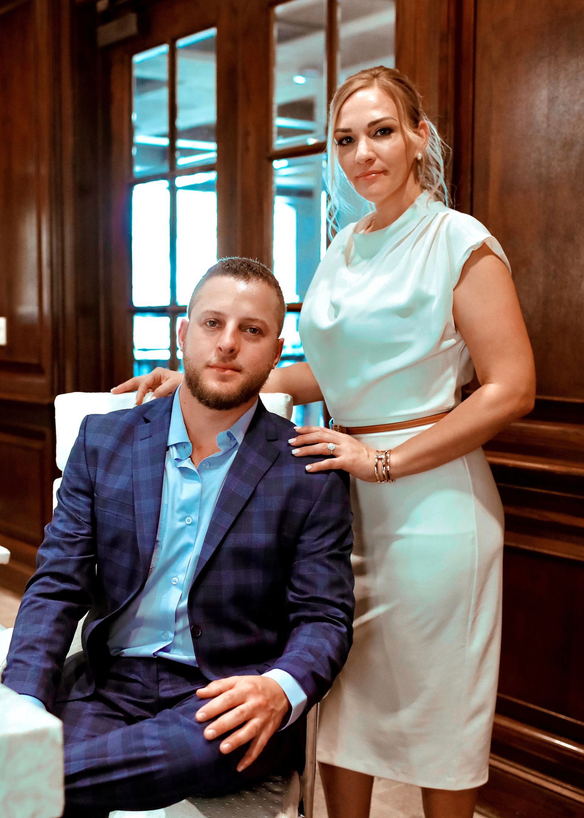 A man in a suit and a woman in a white dress are posing for a picture.
