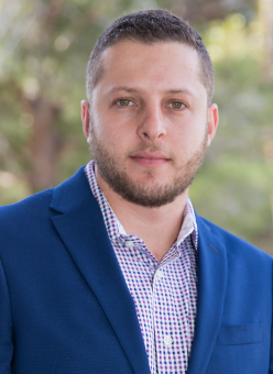 A man with a beard is wearing a blue suit and a plaid shirt.