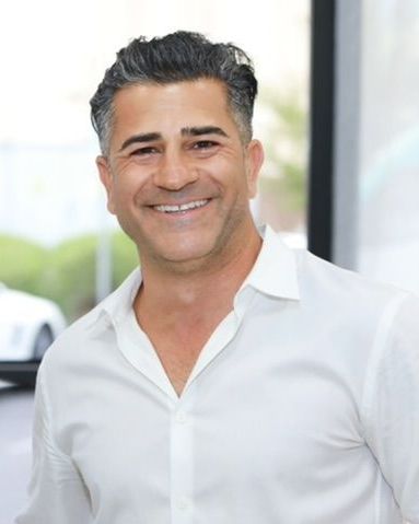 A man in a white shirt is smiling for the camera.