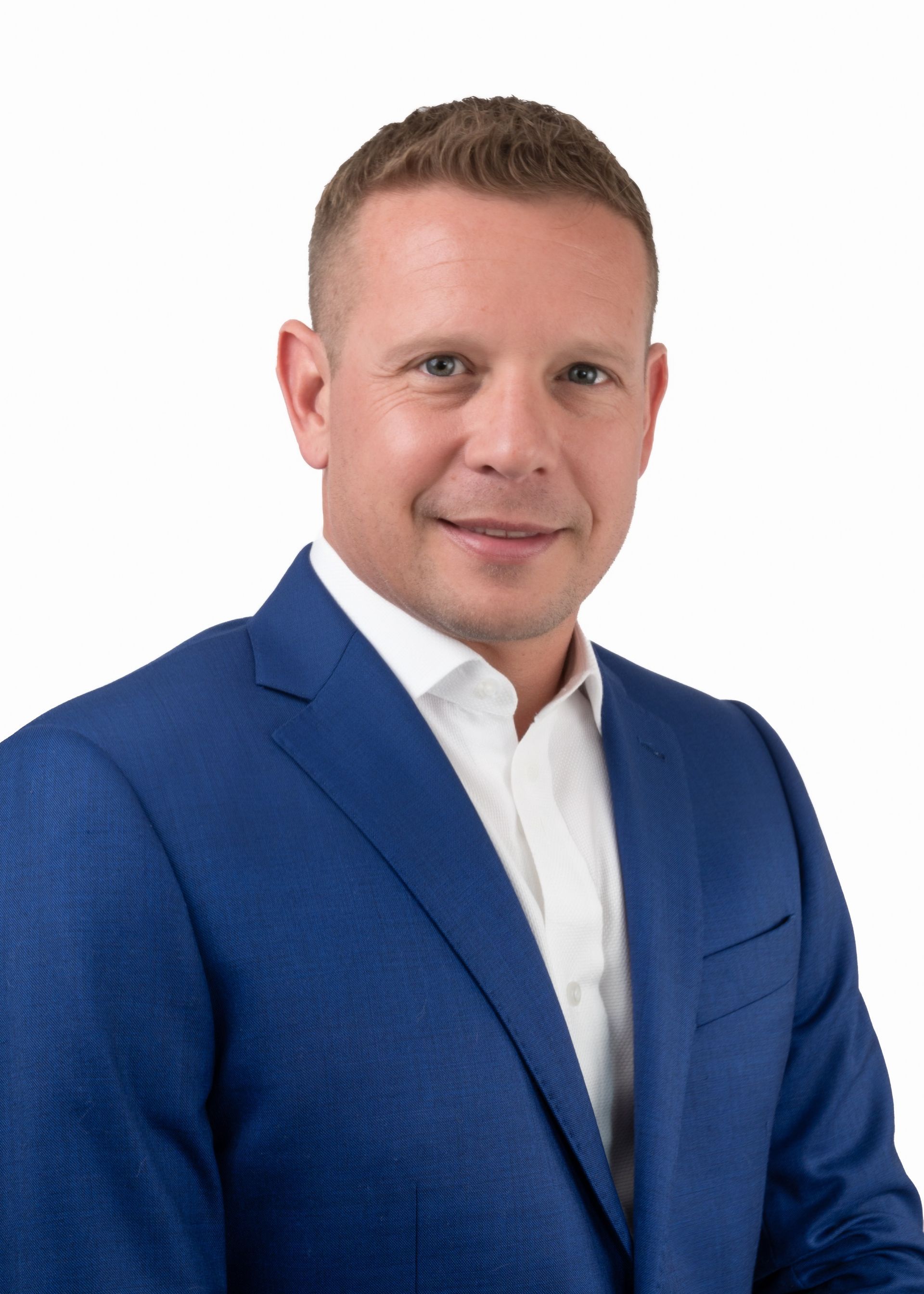 A man in a blue suit and white shirt is smiling for the camera.