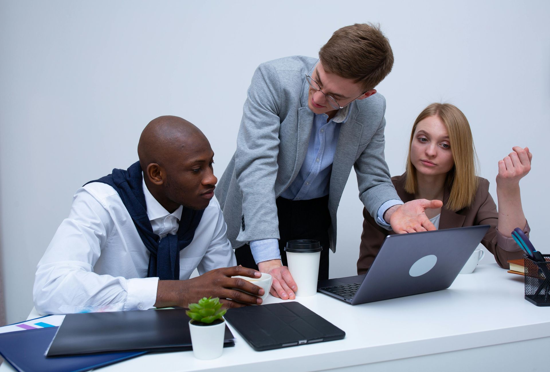 A group of people are sitting at a table looking at a laptop computer.