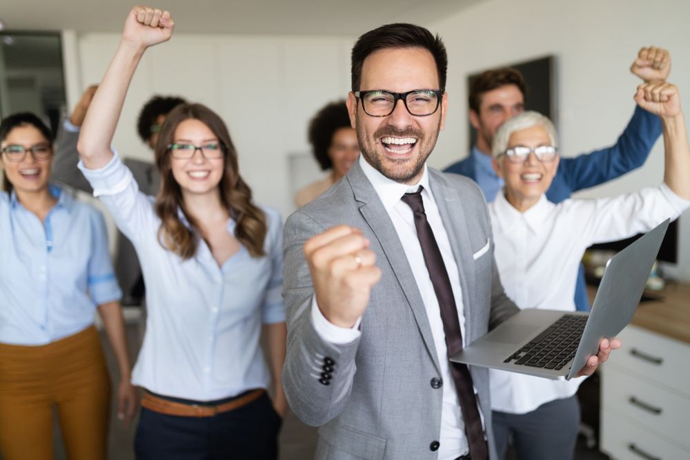 A man is holding a laptop in front of a group of people.