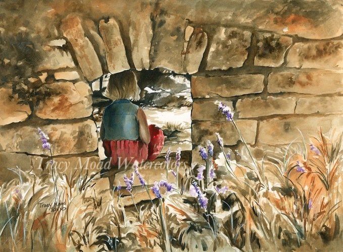Person looking through a stone archway. Pink skirt, dark blue top, lavender flowers and brown grasses in the foreground.