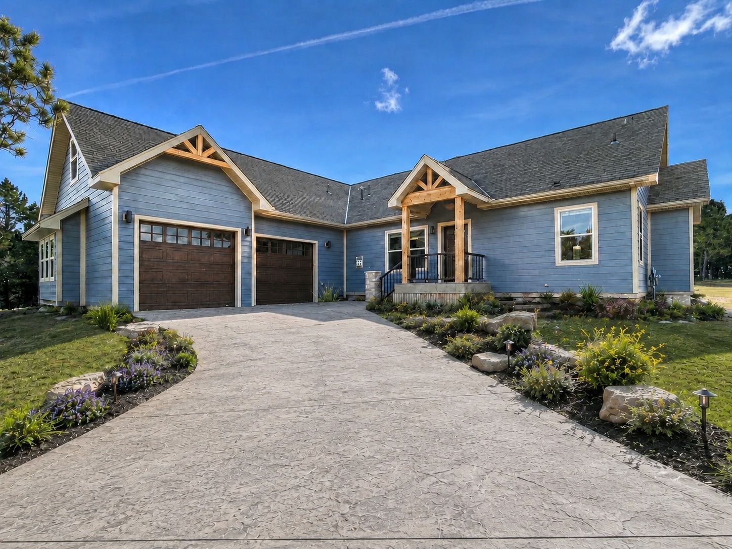 Modern gray house with wood accents, two garage doors, and a stone path through landscaped front yard