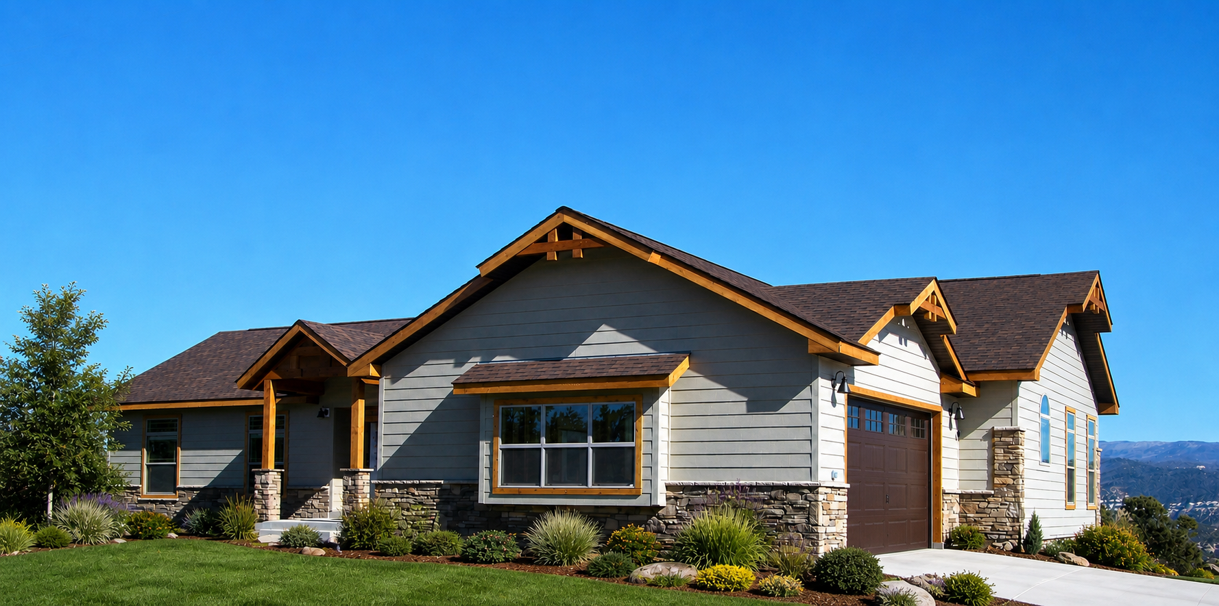 Single-story suburban house with light siding, dark roof, and front porch under a clear blue sky