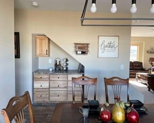 Dining room with dark wood table, fruit centerpiece, and light blue accent wall with sideboard and wall art