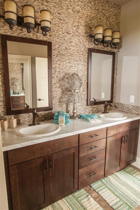 Double vanity bathroom with brown cabinets, two mirrors, and beige mosaic tile walls