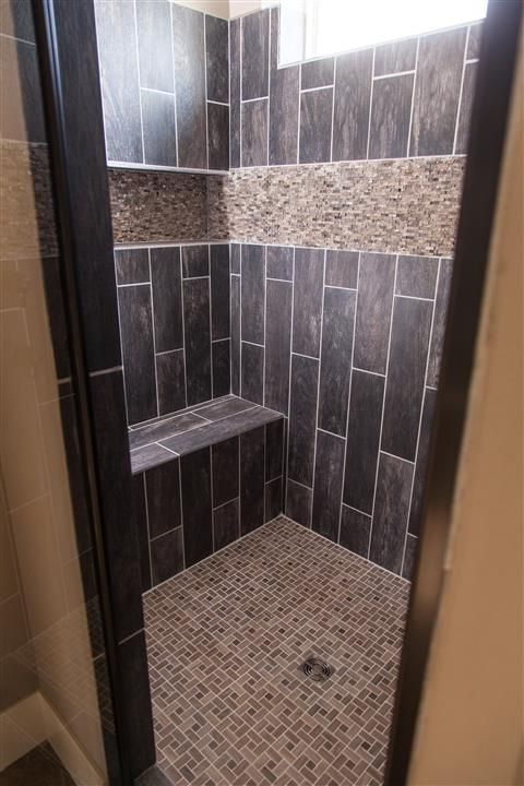 Tiled shower stall with dark gray walls, mosaic accent band, and matching floor tiles