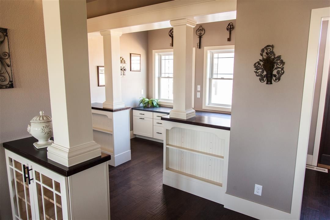 Bright kitchen with white cabinets, dark wood floors, and open view into a living area