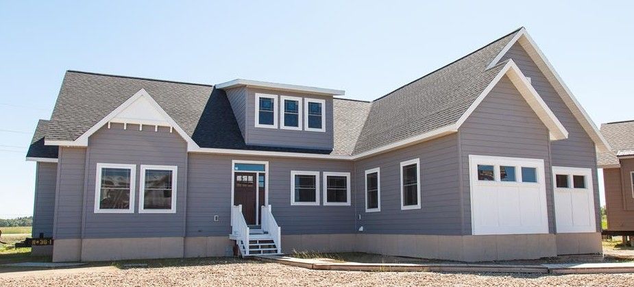 Single-story gray house with white trim, front porch, and attached garage under a clear sky