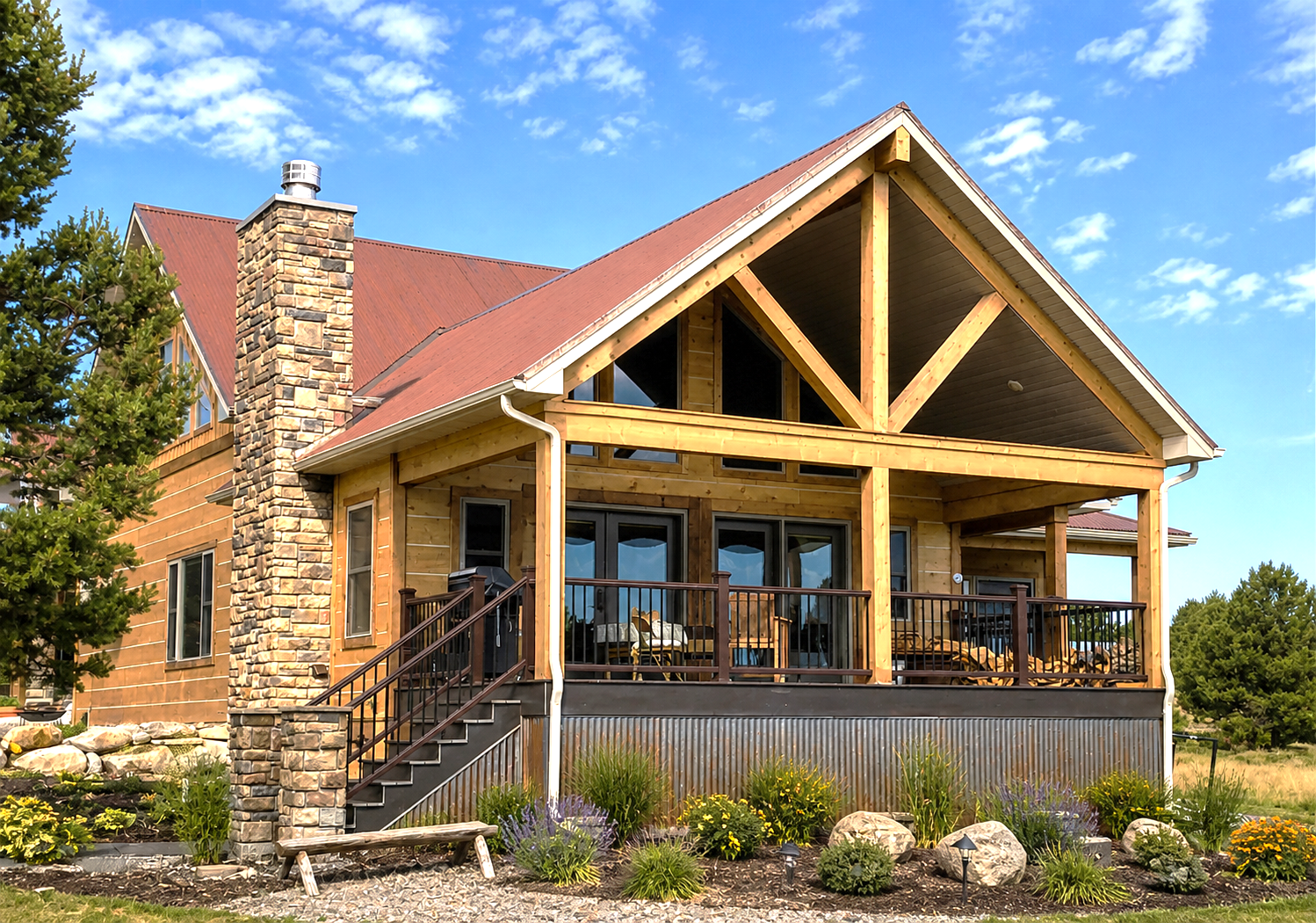 Rustic cabin with red roof, stone chimney, and covered porch under a blue sky