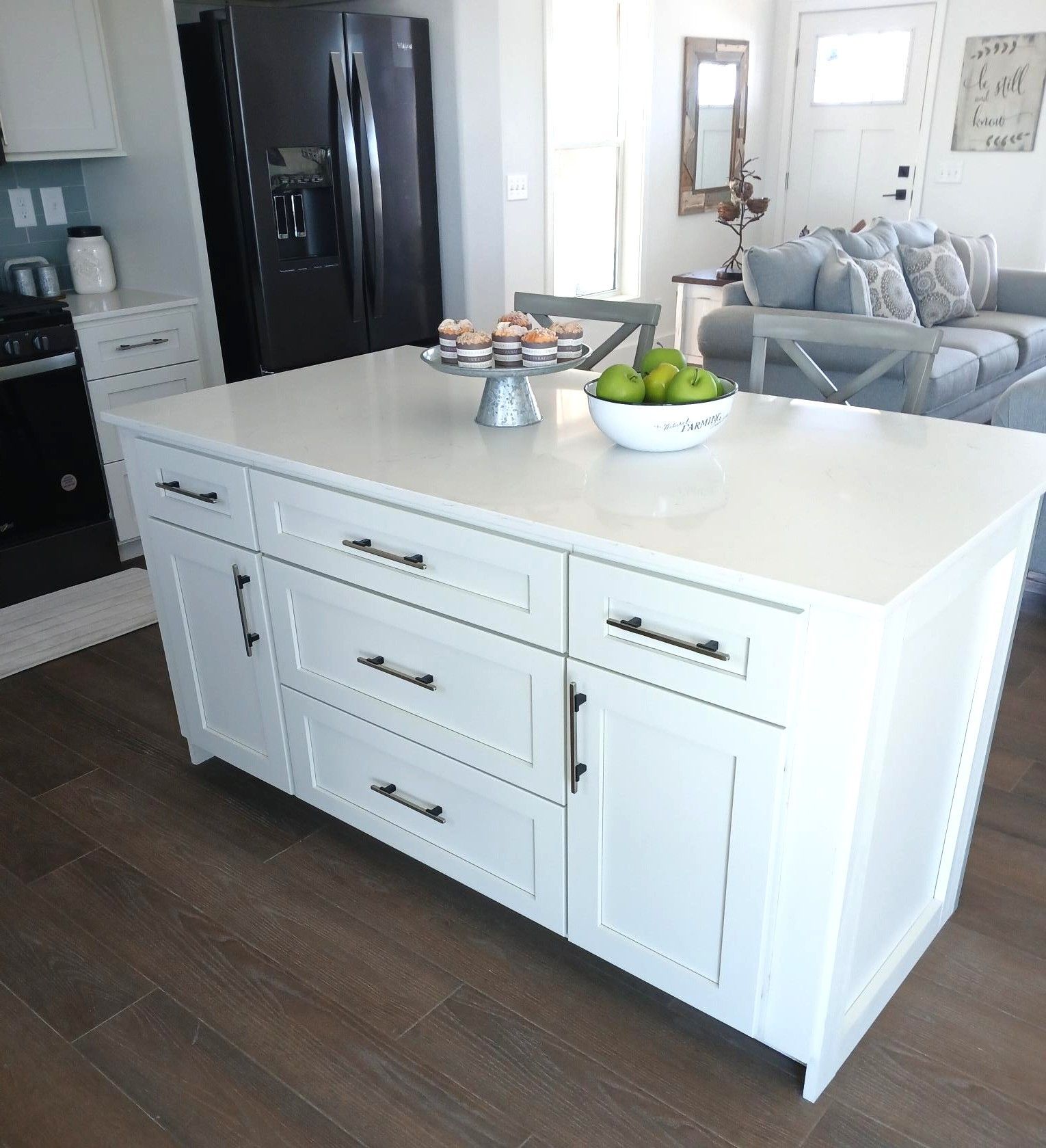 White kitchen island with fruit bowl and cupcakes in a bright open-plan living space