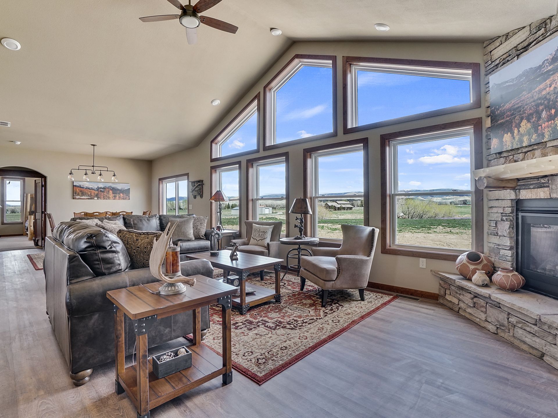 Bright living room with large windows, gray sofa, wooden coffee table, and mountain view outside.