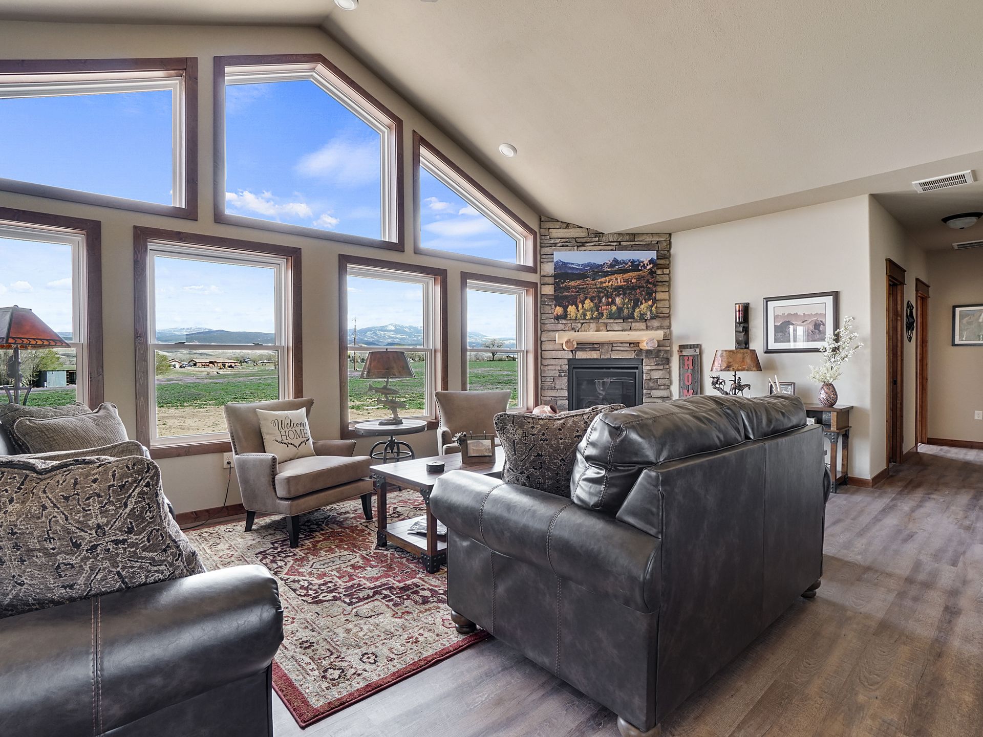 Bright living room with leather sofas, large windows, mountain view, and a red patterned rug