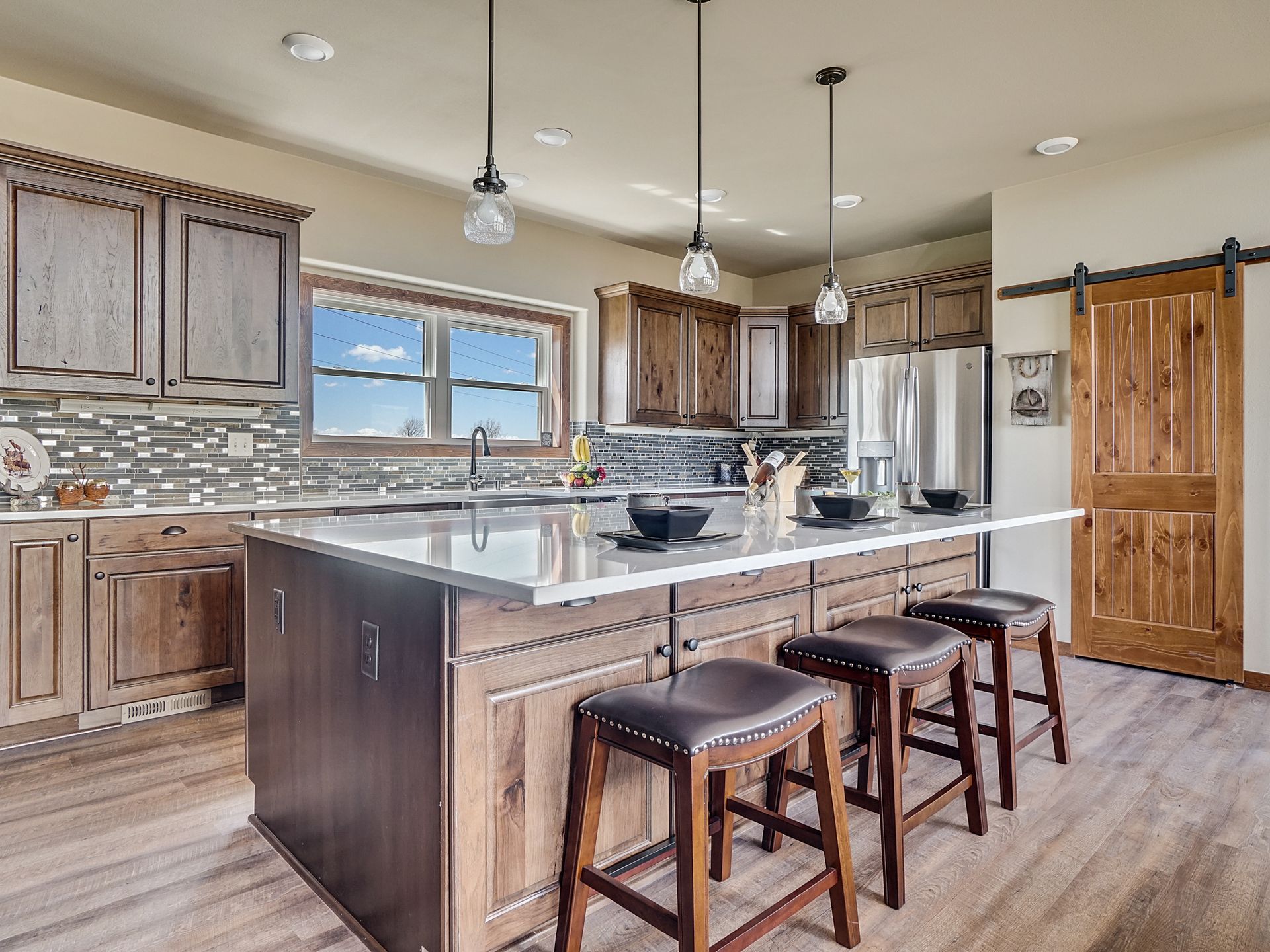 Modern kitchen with island, bar stools, wood cabinets, and large windows
