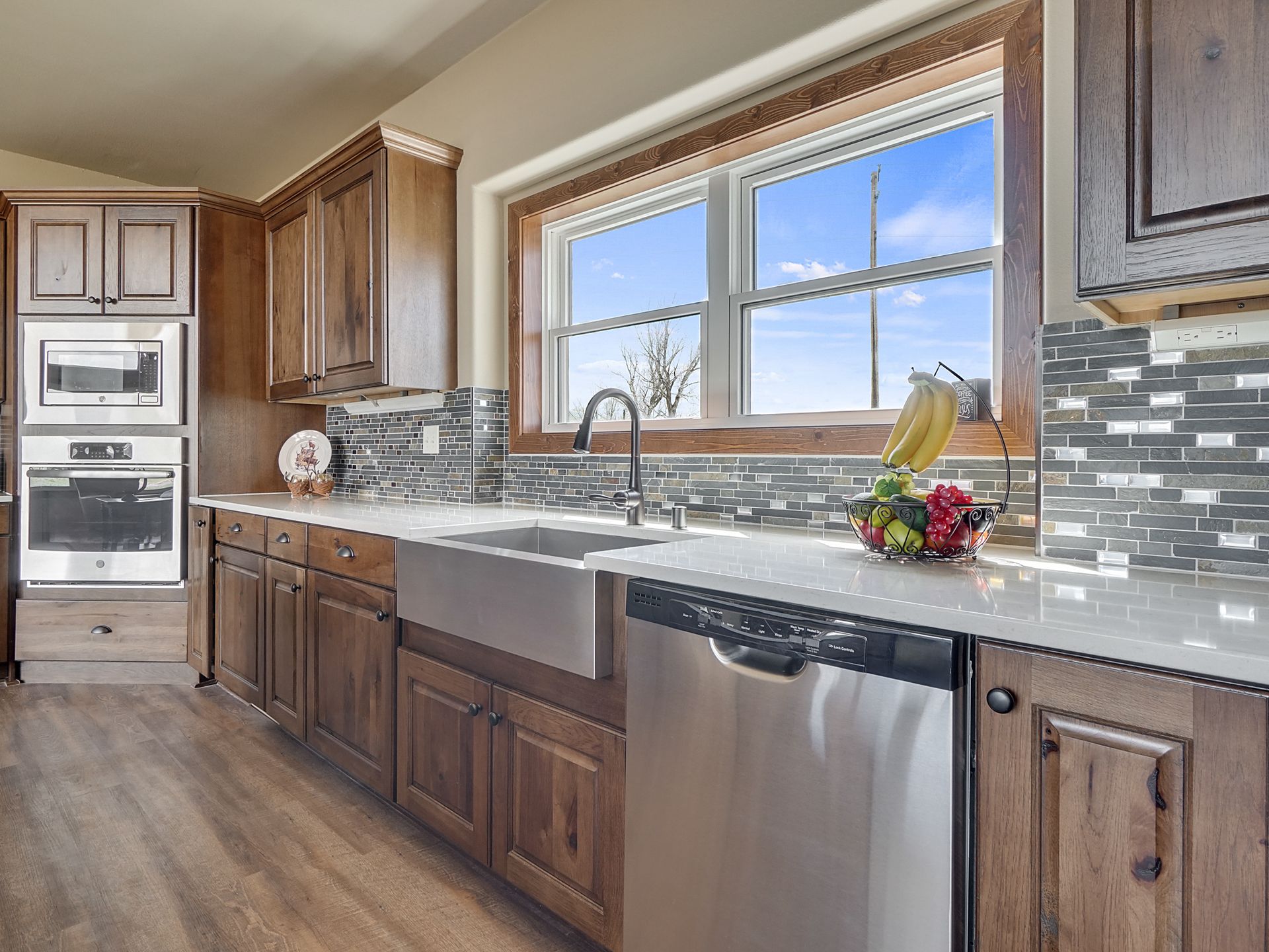 Modern kitchen with wooden cabinets, stainless appliances, large window, and granite countertops
