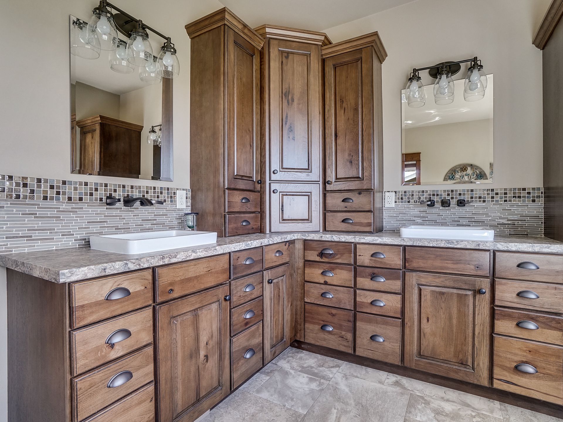 Bathroom vanity with double sinks, wood cabinets, granite countertop, and wall mirrors