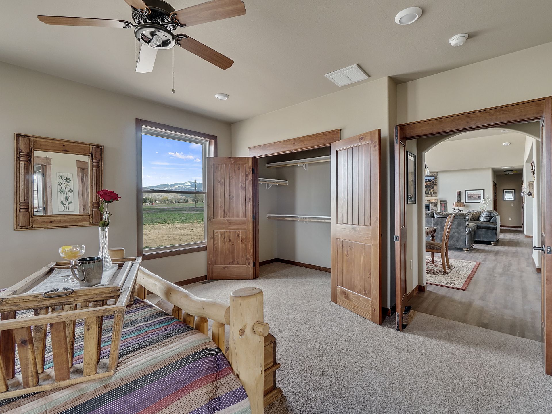 Bedroom with open closets, ceiling fan, and a view through windows to fields outside