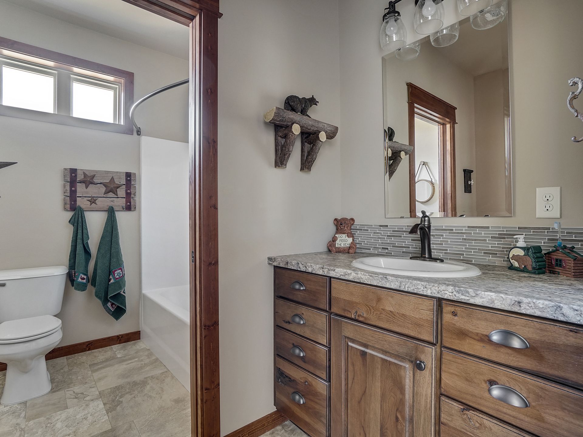 Bathroom with double vanity, granite countertop, mirror, and towel hanging beside a toilet and tub.
