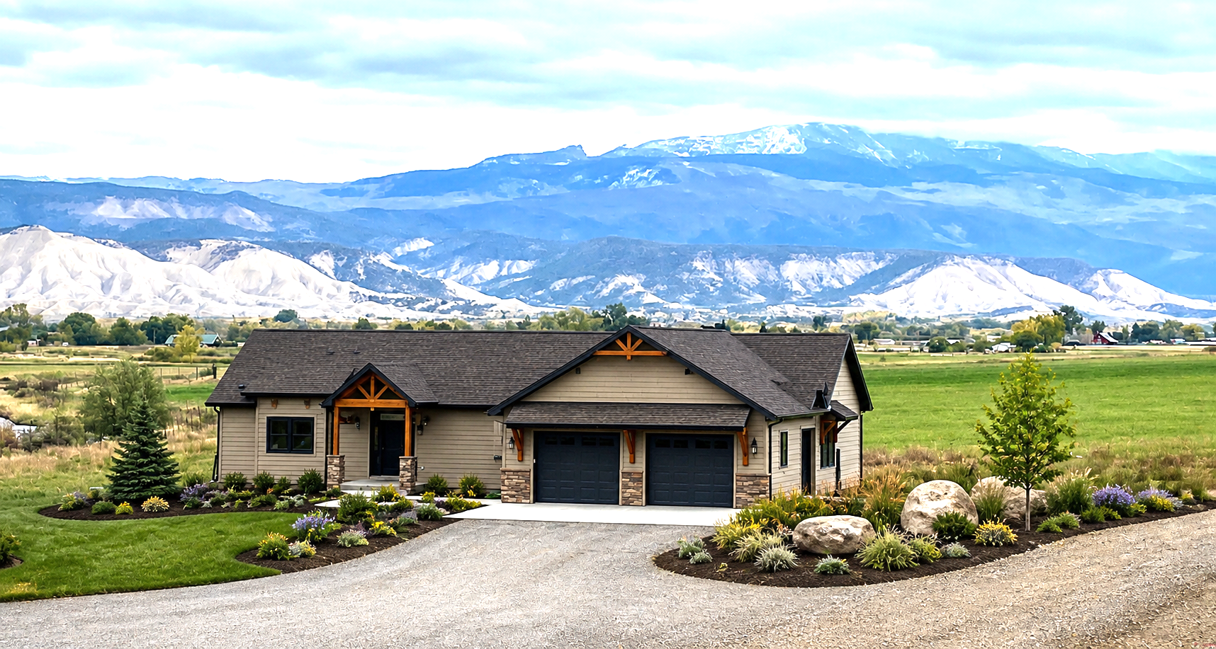 Single-story house with gravel driveway, green lawn, and snow-capped mountains in the background