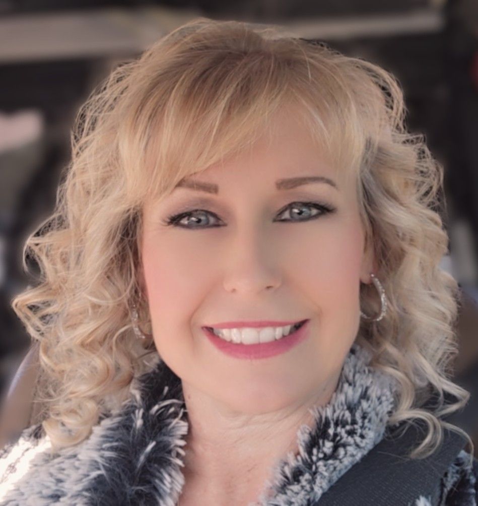 Smiling portrait with blonde curls and a black-and-white fur collar outdoors