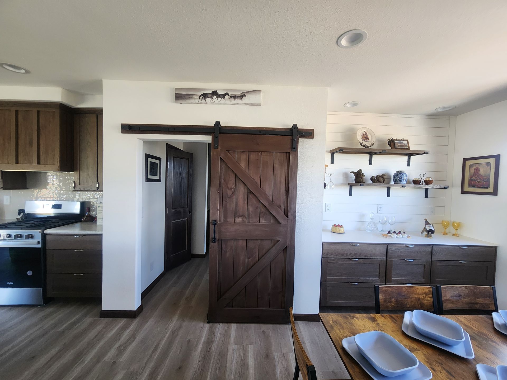 Modern kitchen and dining area with dark wood cabinets, barn door, and blue placemats on a table