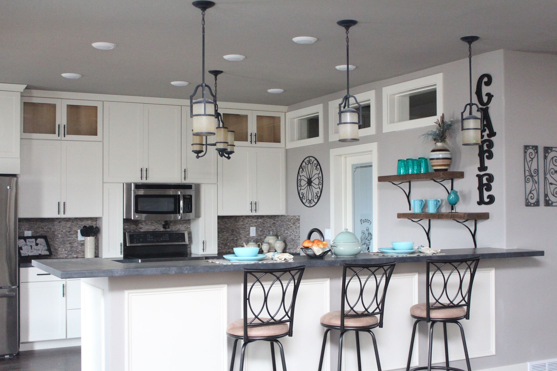 Bright modern kitchen with white cabinets, gray island, bar stools, and hanging pendant lights
