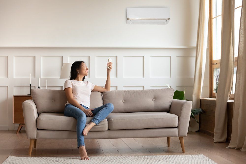 Woman on Couch Enjoying Air Conditioning — Electrical Services in Cairns, QLD