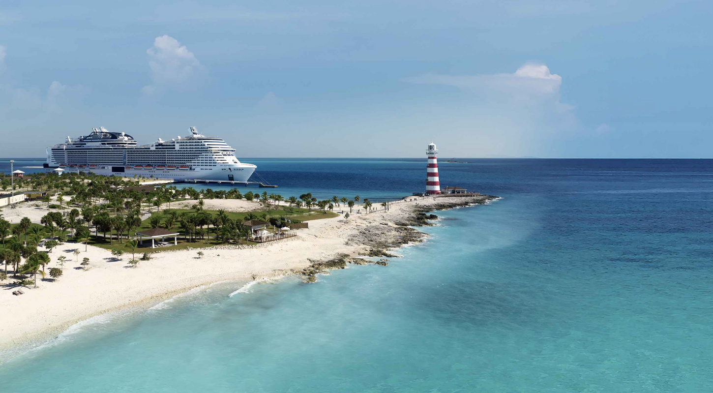 Cruise ship at a tropical island beach with a lighthouse and turquoise water.