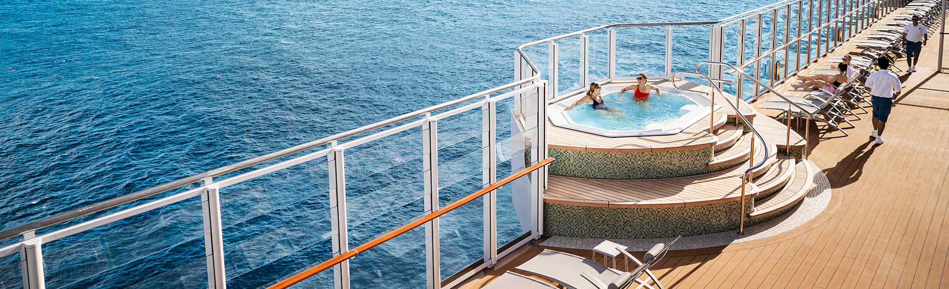 Hot tub on a cruise ship deck with two people. Ocean in the background.