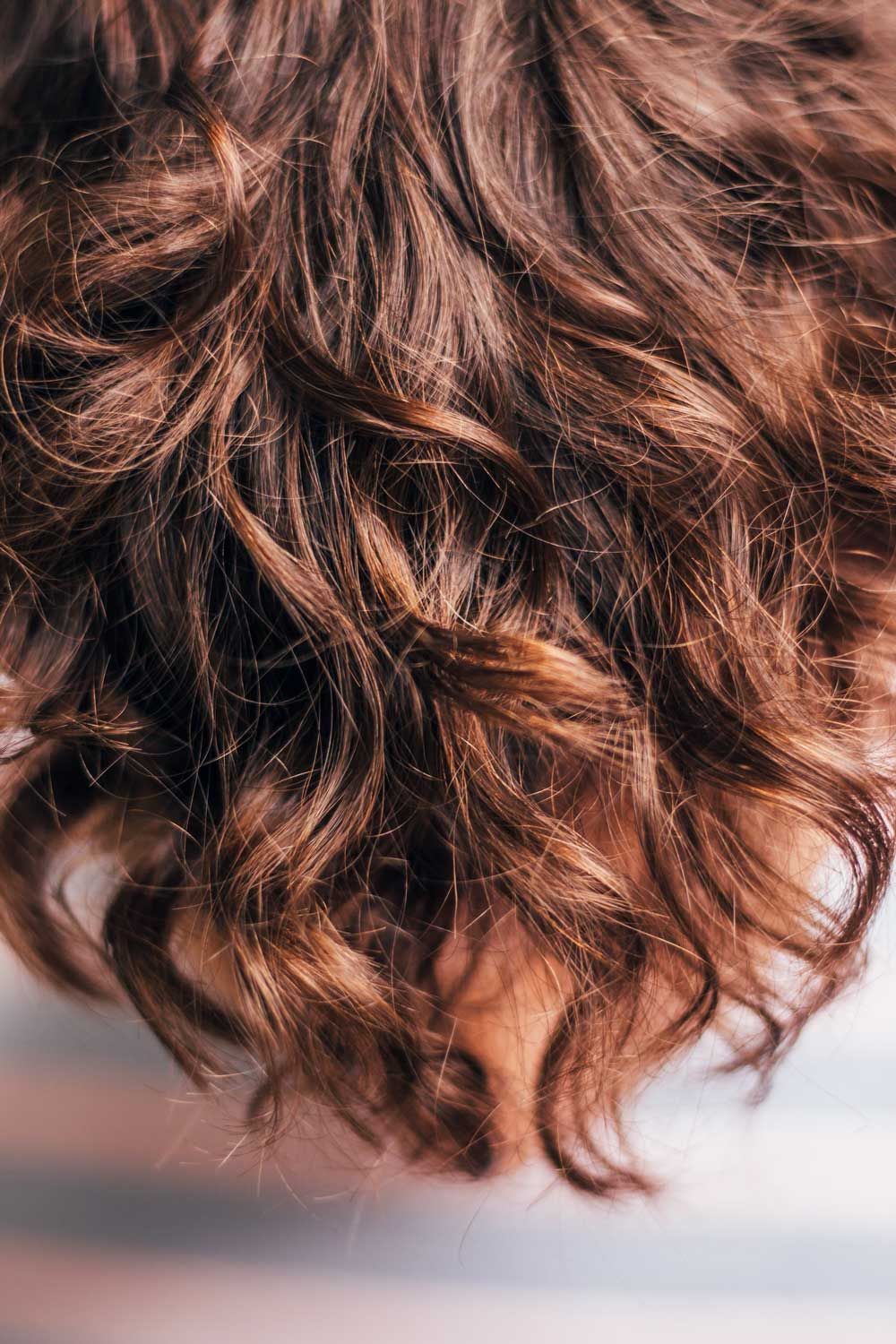 Close-up of soft brunette curls styled with shine by Ballarat Hairdressers.