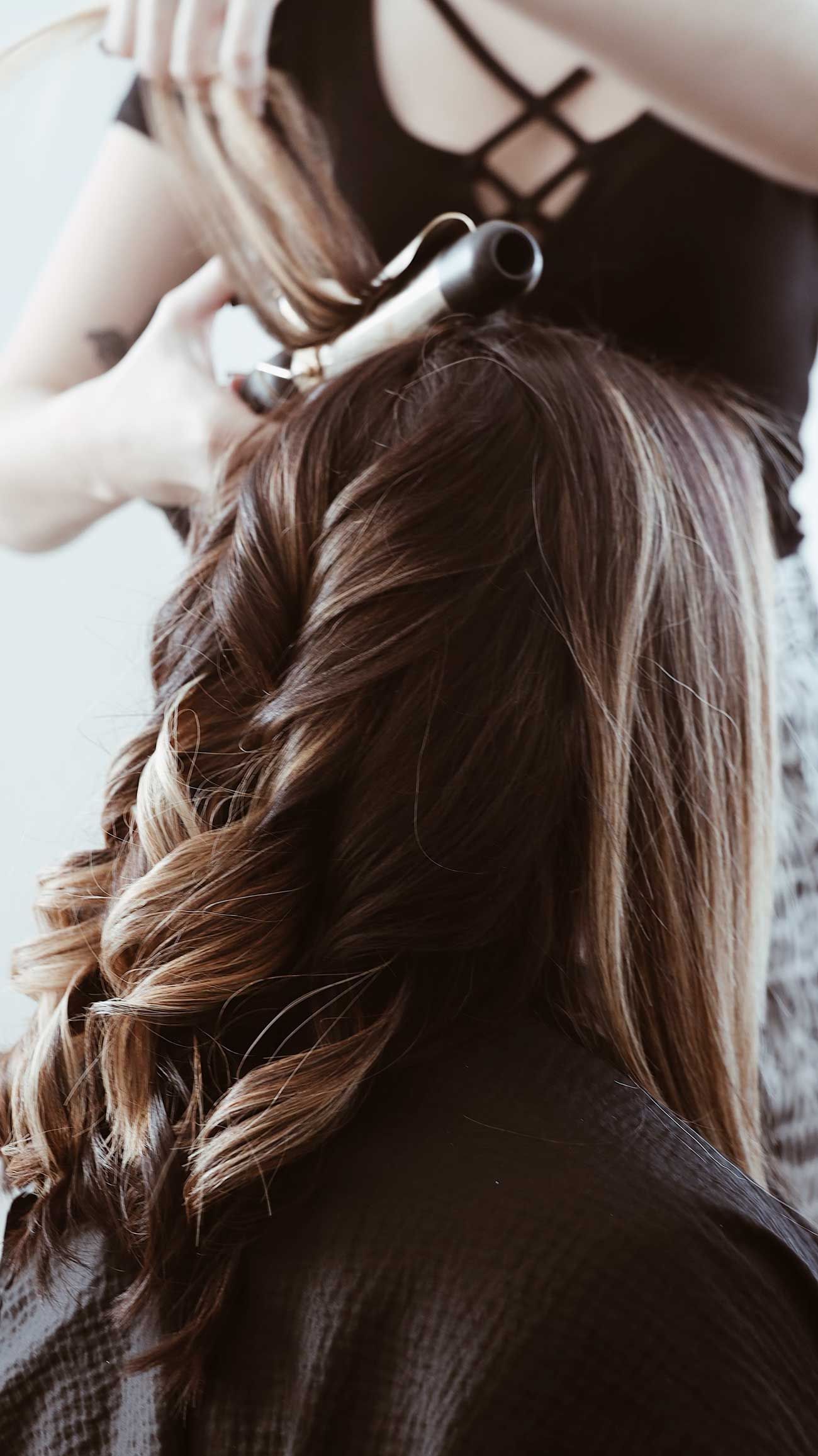 Hairdresser creating loose curls with a curling iron at a Ballarat hair salon.