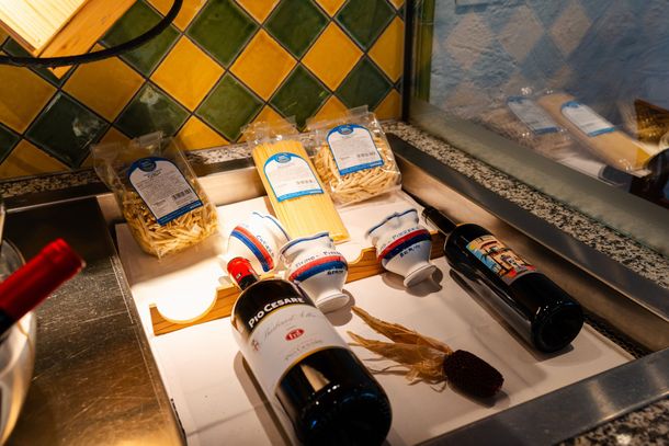 Weinflaschen und eingepackte Geschenkkörbe auf einer gefliesten Theke in einem Schaufenster.