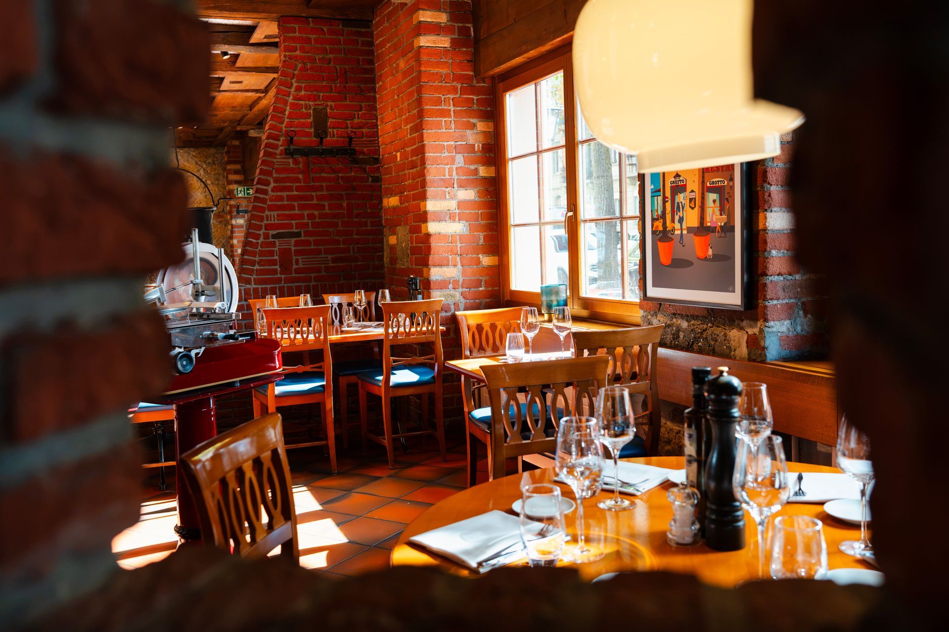 Gemütliches Restaurant mit Backsteinwänden, gedeckten Tischen, warmem Licht und großen Fenstern