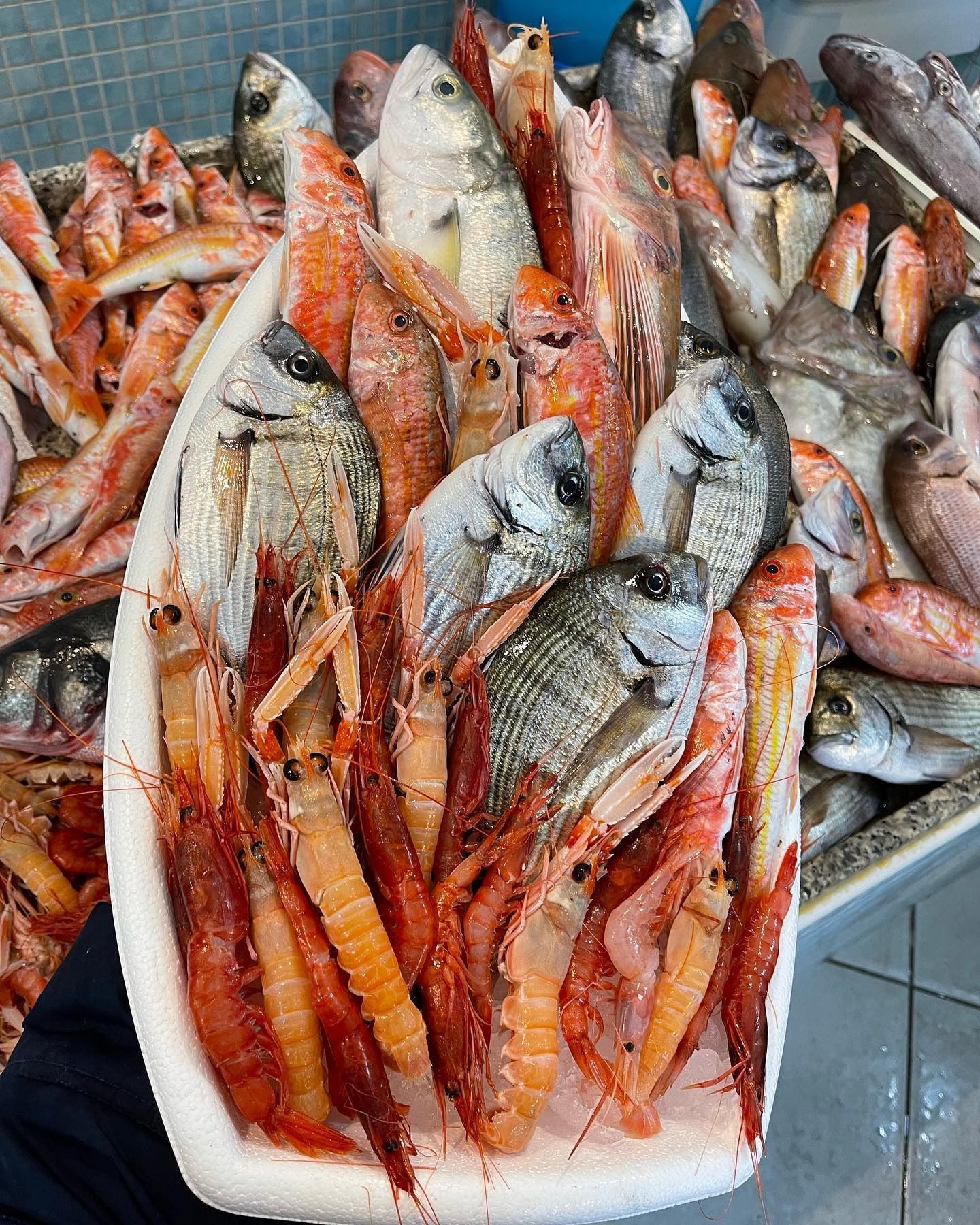 Vassoio di pesce fresco e gamberetti sul ghiaccio in una bancarella del mercato.