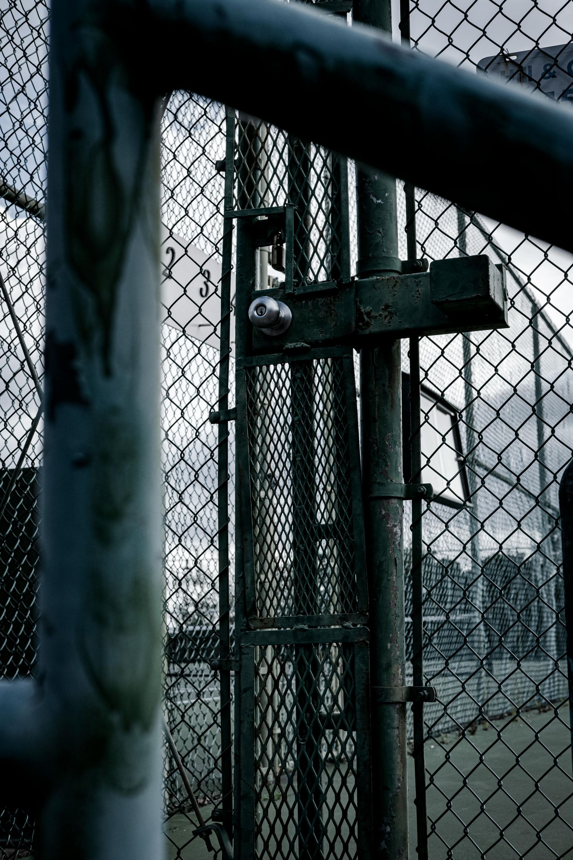 A close up of a chain link fence with trees in the background.