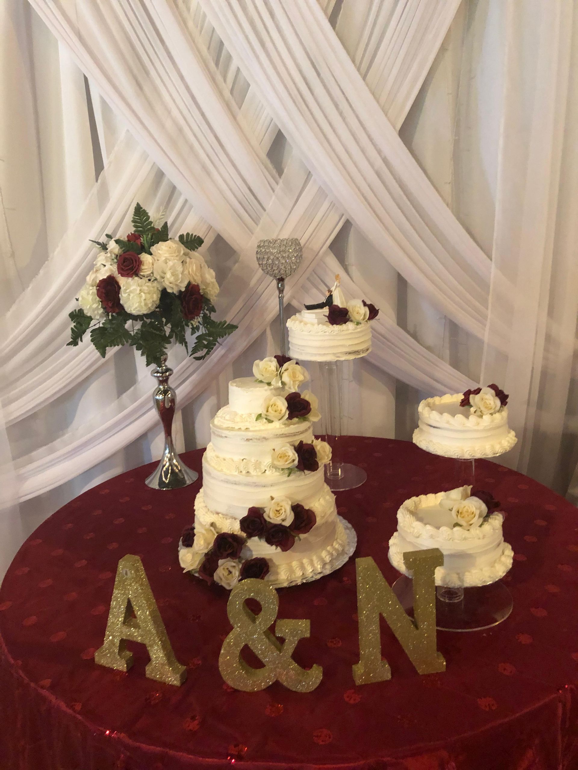 A wedding cake display on a red table with glittery 