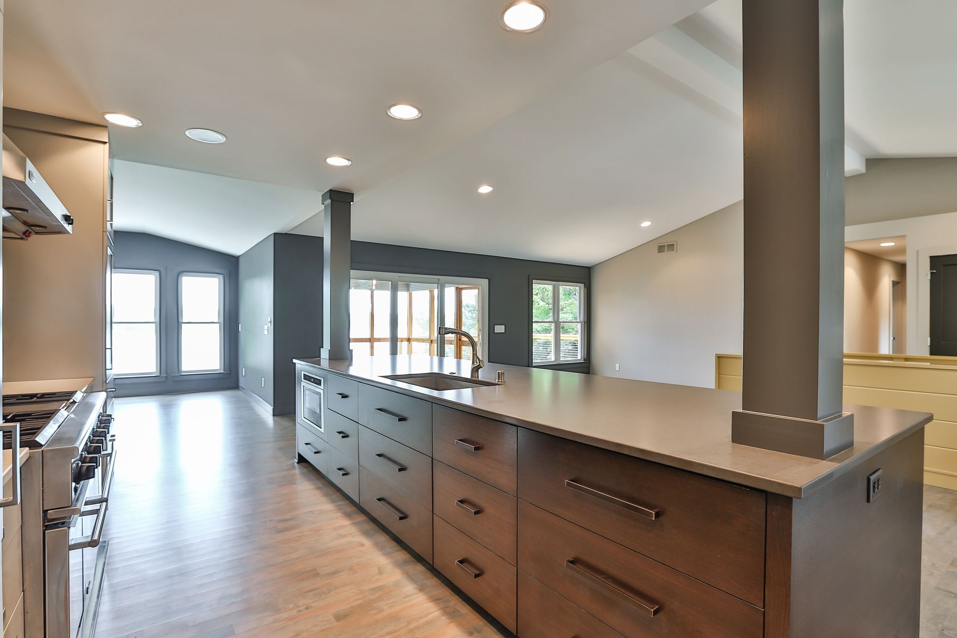 Modern kitchen with dark wood cabinetry, gray countertop, and open layout.