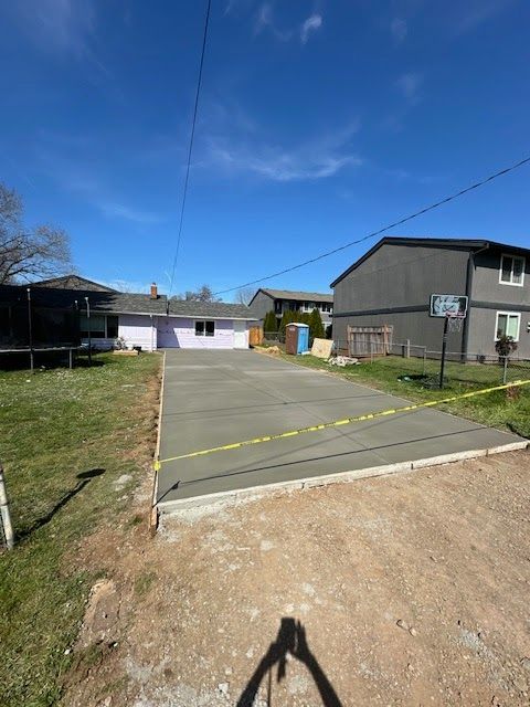 Newly poured concrete driveway in a residential yard, secured with caution tape.