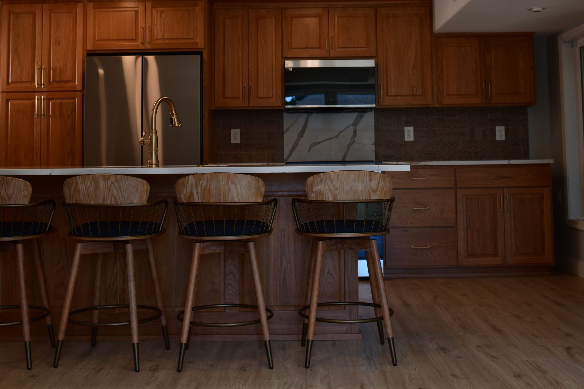 Kitchen with wood cabinets, island with stools, and stainless steel appliances.
