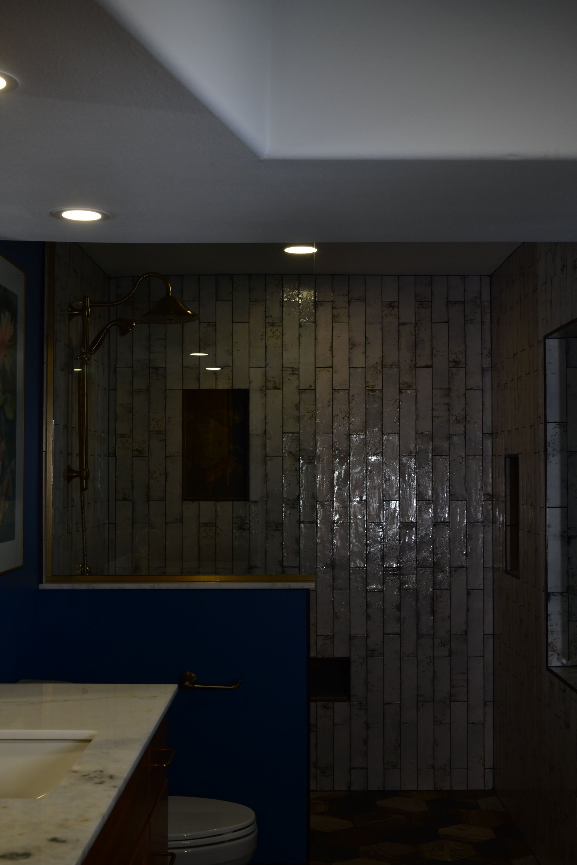 Bathroom with patterned tile shower, glass enclosure, and blue walls.