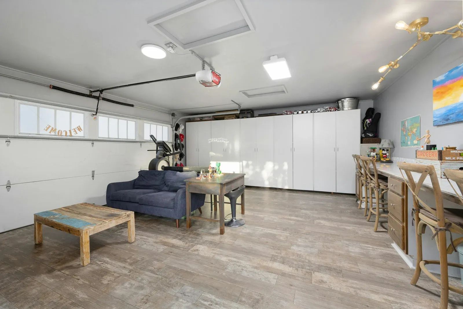 Finished garage converted into a living space with seating, cabinets, and a bar area.