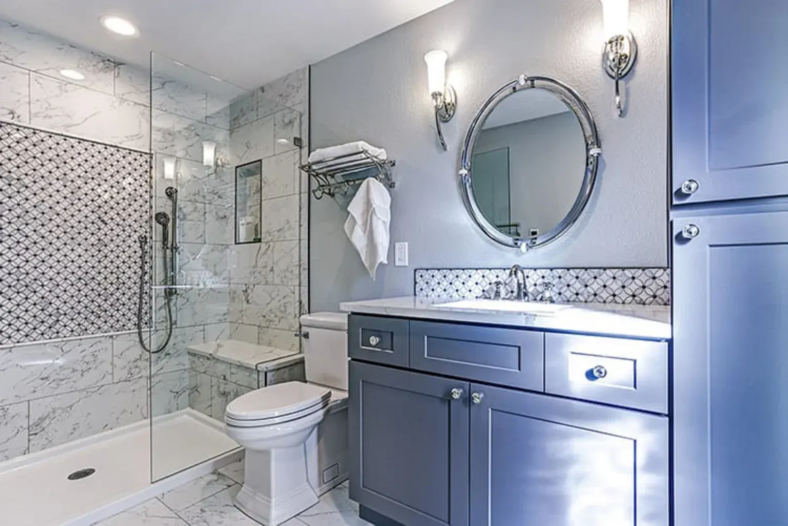 Modern bathroom with glass shower, gray vanity, and decorative tile.