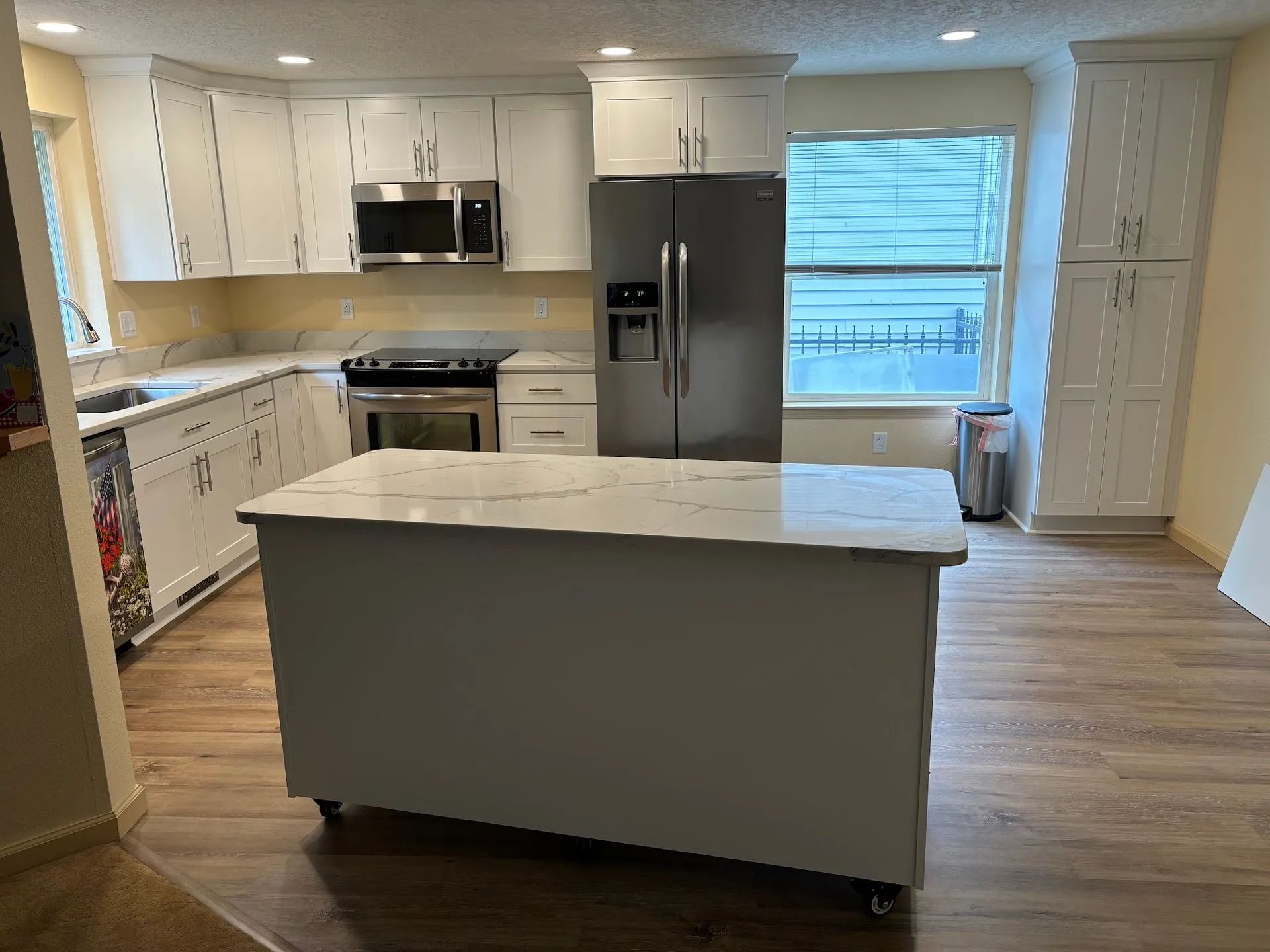 Bright modern kitchen with white cabinets, stainless appliances, and a large island in the center.