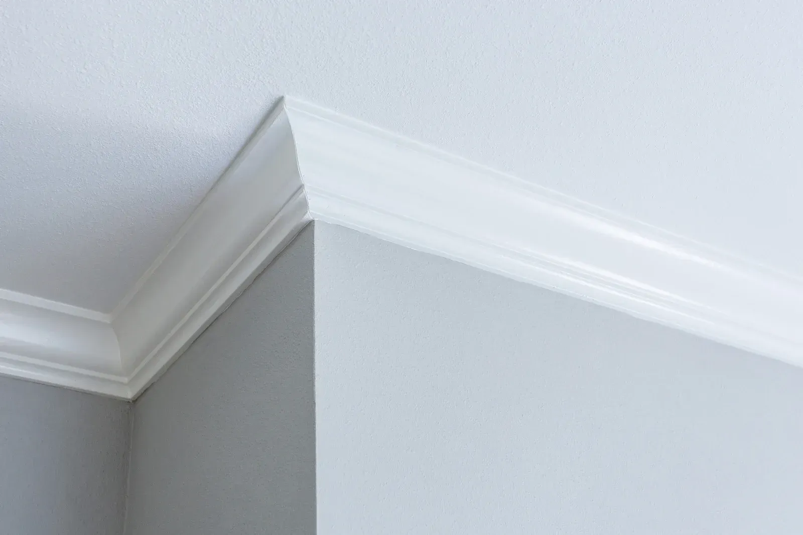 White crown molding at the corner where a white ceiling meets gray and white walls.