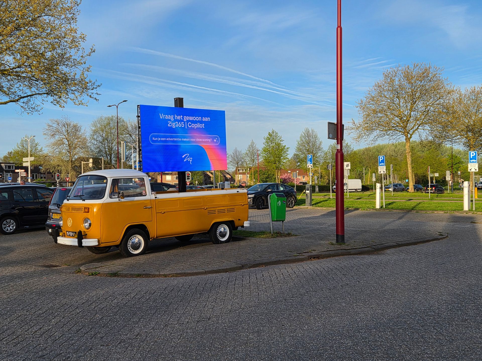 Een gele volkswagen bus met ledscherm  op een zonnige parkeerplaats 