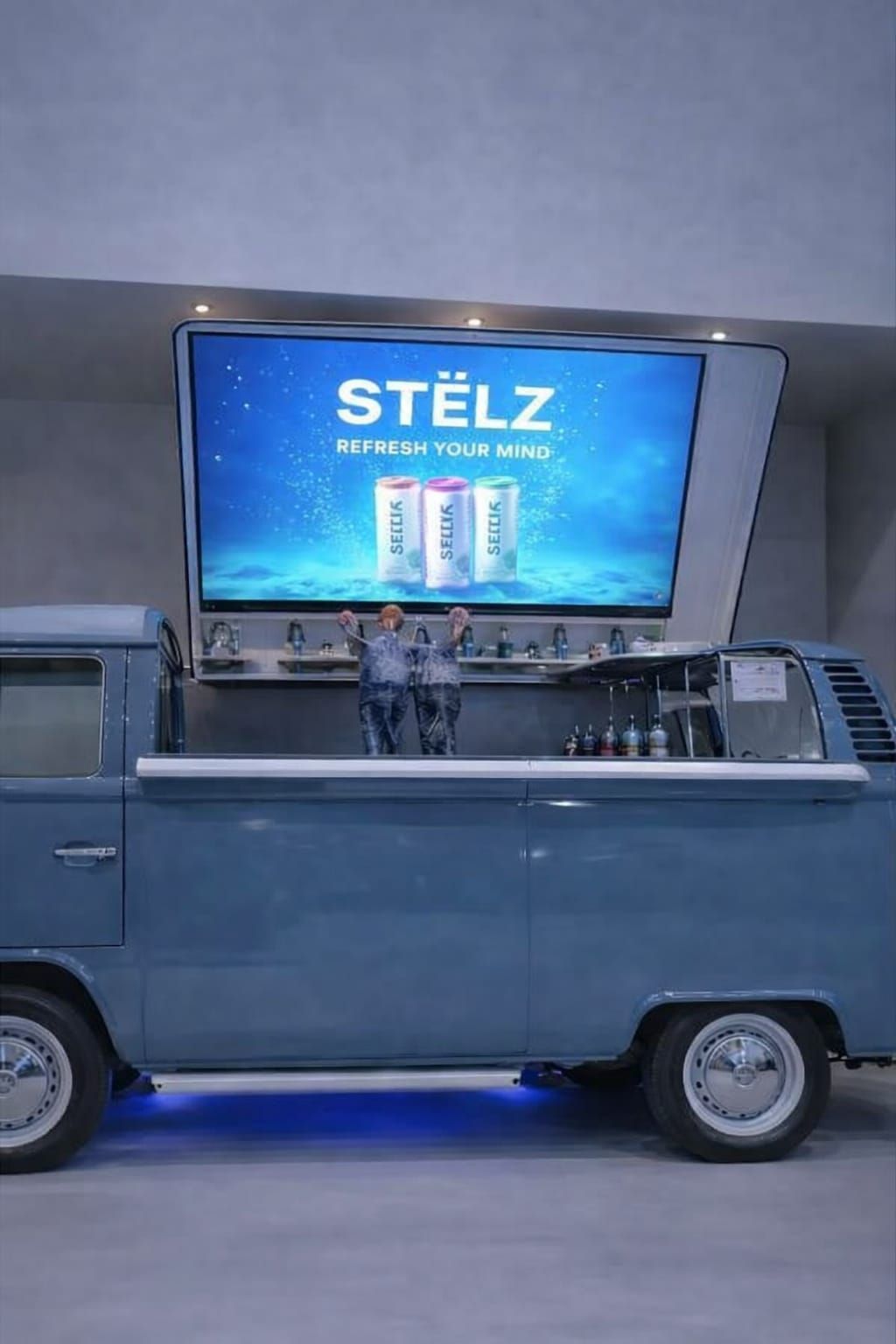 Blauwe volkswagne foodtruck met groot scherm en een open serveerluik.